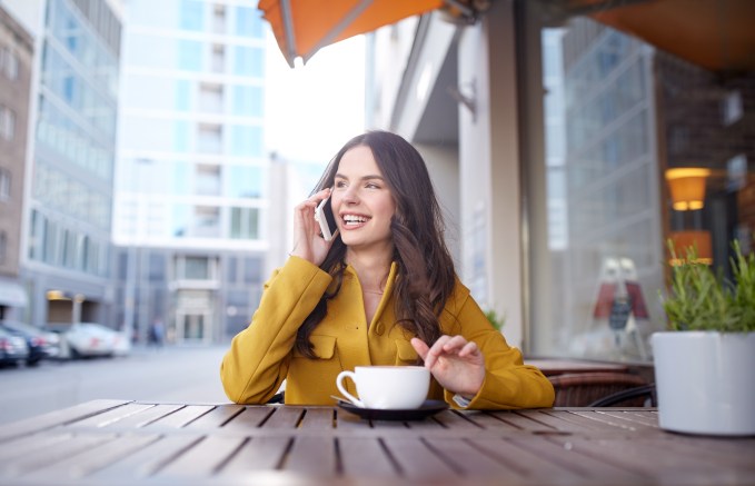 happy woman calling on smartphone at city cafe